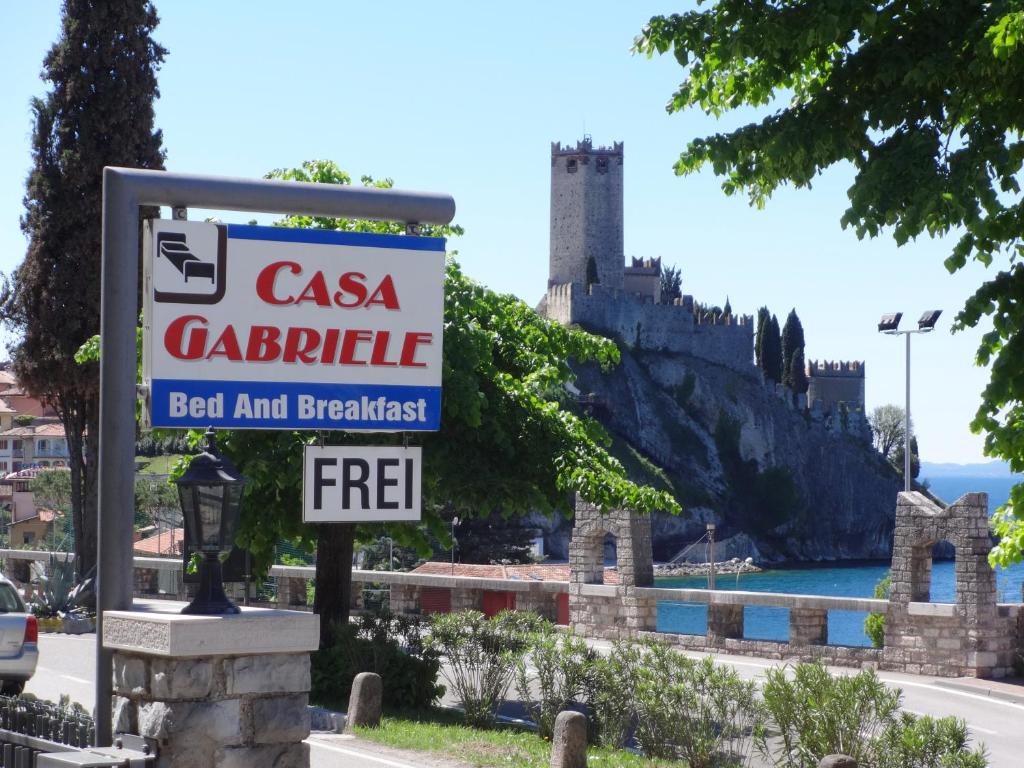 a sign for a car dealership with a castle in the background at B&B Casa Gabriele in Malcesine