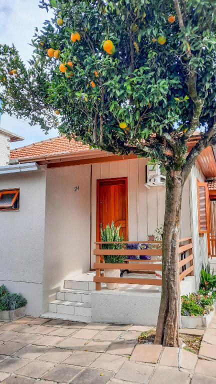 a bench in front of a house with an orange tree at Hospedagem Don Panizzi in Bento Gonçalves