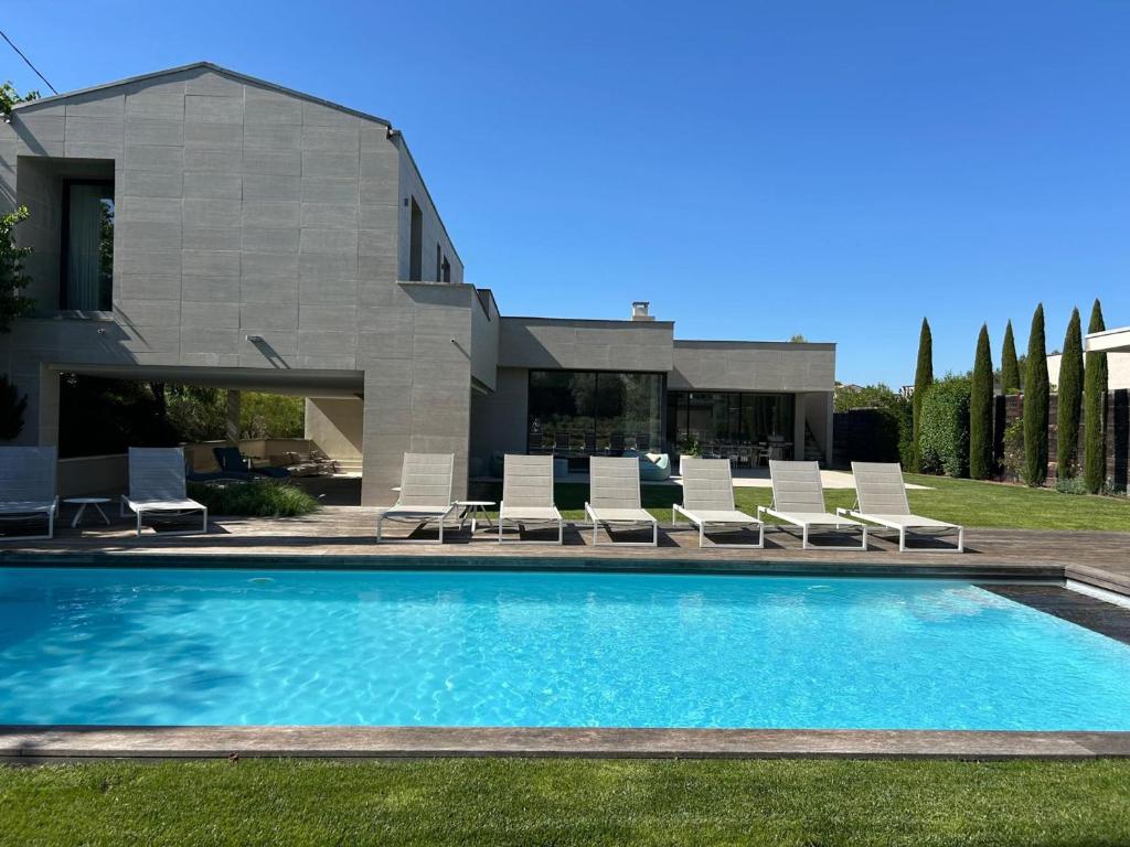 une piscine avec des chaises et une maison dans l'établissement Villa contemporaine avec piscine proche centre de Saint-Rémy-de-Provence - FR-1-599-43, à Saint-Rémy-de-Provence