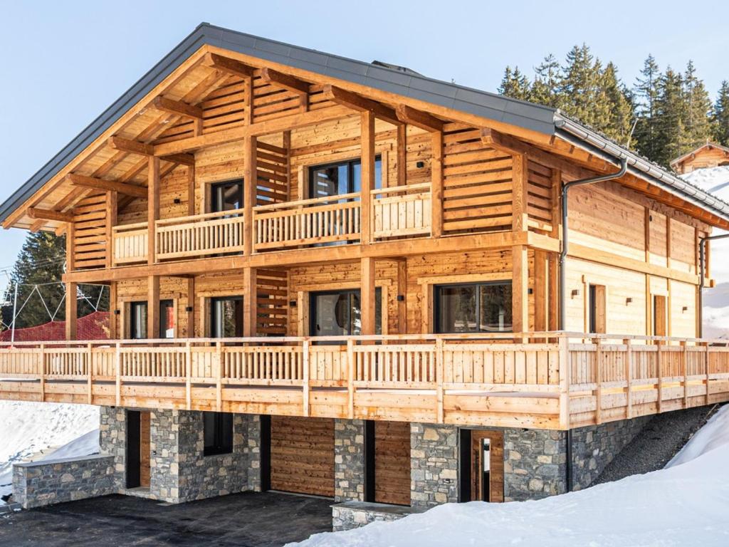 une cabane en rondins entourée d'une terrasse dans la neige dans l'établissement Demi-chalet haut de gamme 3 chambres à La Clusaz avec vues superbes - FR-1-459-243, à La Clusaz