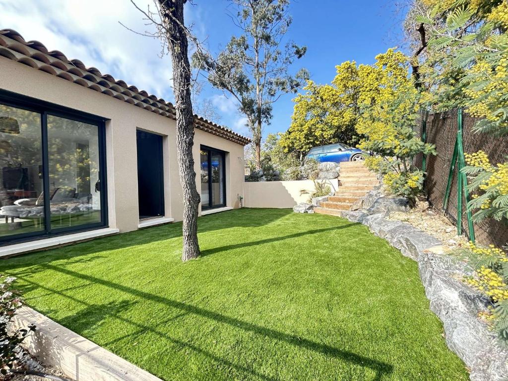 une cour avec de l'herbe verte et un arbre dans l'établissement Maison neuve 3 pièces avec terrasse à Grimaud - FR-1-226-558, à Grimaud