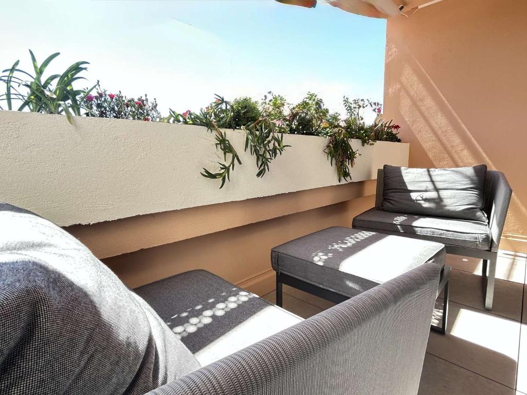 Elle comprend un balcon avec deux chaises et une fenêtre ornée de plantes. dans l'établissement Studio cosy à Sainte-Maxime avec parking sécurisé - FR-1-226-560, à Sainte-Maxime