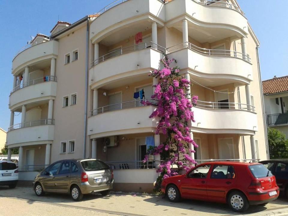 a building with cars parked in front of it at Apartments Angie in Biograd na Moru