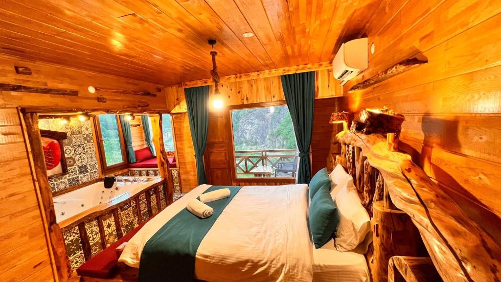 a bedroom in a log cabin with a bed and a tub at panoramabungalov in Çamlıhemşin
