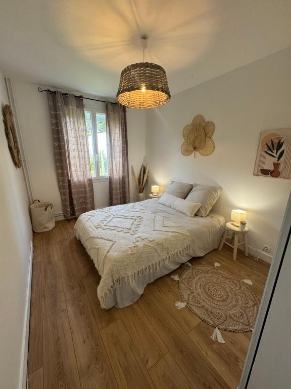 une chambre avec un grand lit et un lustre dans l'établissement Le Verger de Manou, à Saint-Palais-sur-Mer