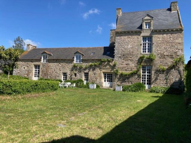 une grande maison en pierre avec une grande cour dans l'établissement Manoir 15 mn des plages, à Hénansal