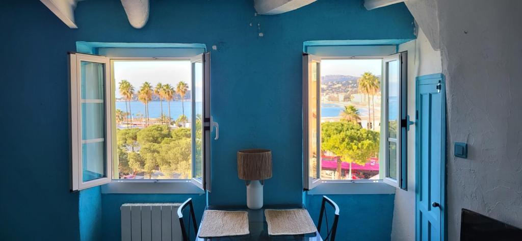 a blue room with two chairs and two windows at Spectacular Seaview & Sunset Studio in Old Town in Menton