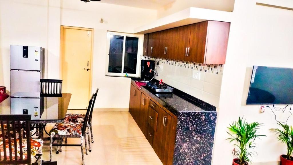 a kitchen with a refrigerator and a table with chairs at Safron Modern Stay at Varca, Goa in Varca