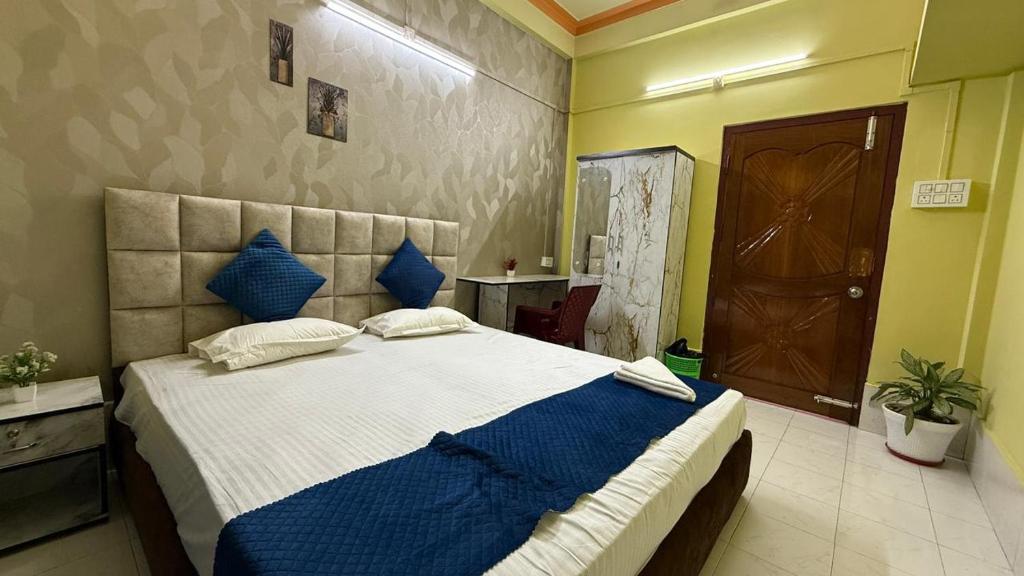 a bedroom with a large bed with blue pillows at Comfort home stay in Sivasagar