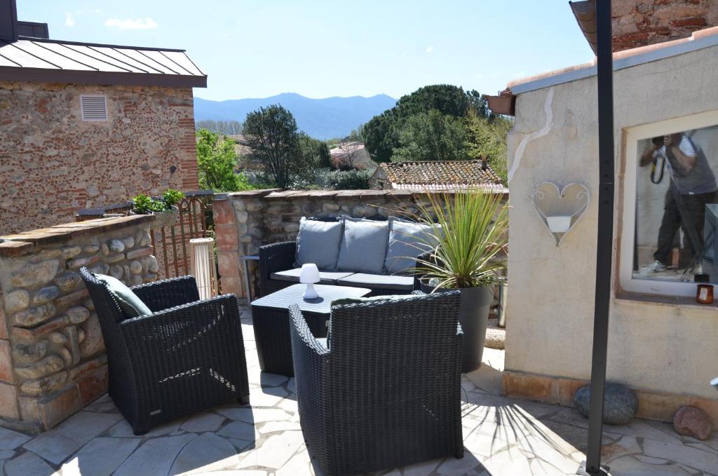 eine Terrasse mit einem Tisch und Stühlen an einer Steinmauer in der Unterkunft Maison de village palau del vidre in Palau-del-Vidre