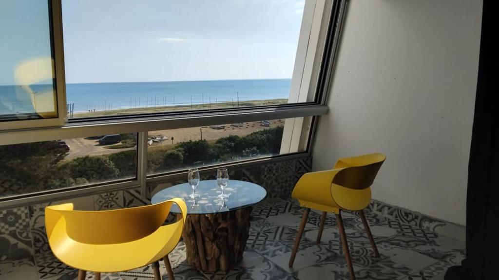 une table et deux chaises jaunes dans une pièce avec une fenêtre dans l'établissement Studio mer escatade, à Saint-Jean-de-Monts