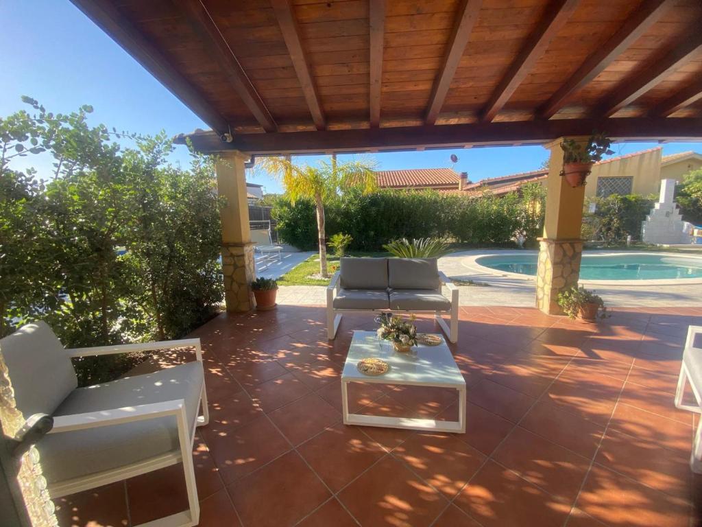 a patio with chairs and a table and a pool at Villetta SCHIRÒ - BAGNASCO in Campofelice di Roccella