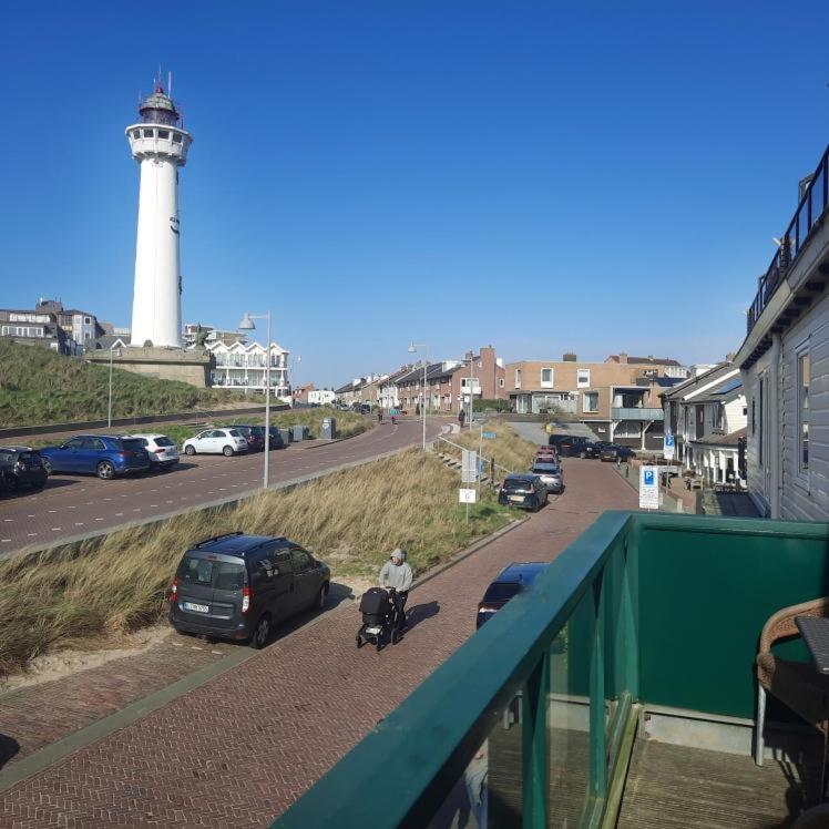 a man walking a bike next to a lighthouse at Torenlicht - Zand I (36) in Egmond aan Zee
