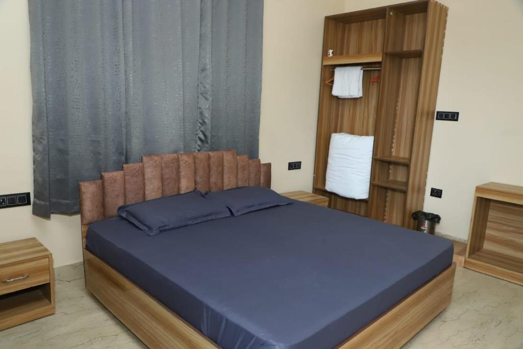 a bedroom with a blue bed with a wooden headboard at Evara Homestay in Dwārīkhāl