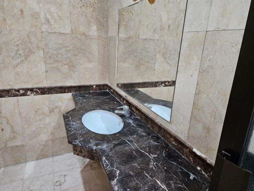 ein Badezimmer mit einer schwarzen Marmorablage und einem Spiegel in der Unterkunft Grand Valora 1 in Semarang