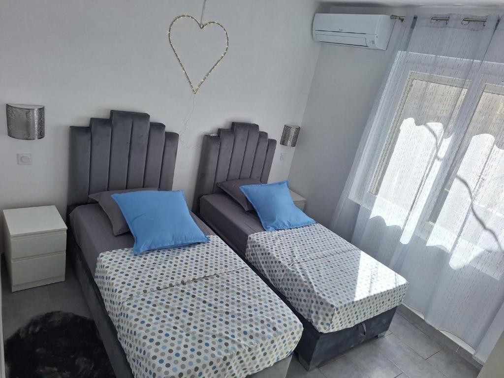 une chambre avec deux lits avec des oreillers bleus et un cœur sur le mur dans l'établissement love sormiou, à Marseille