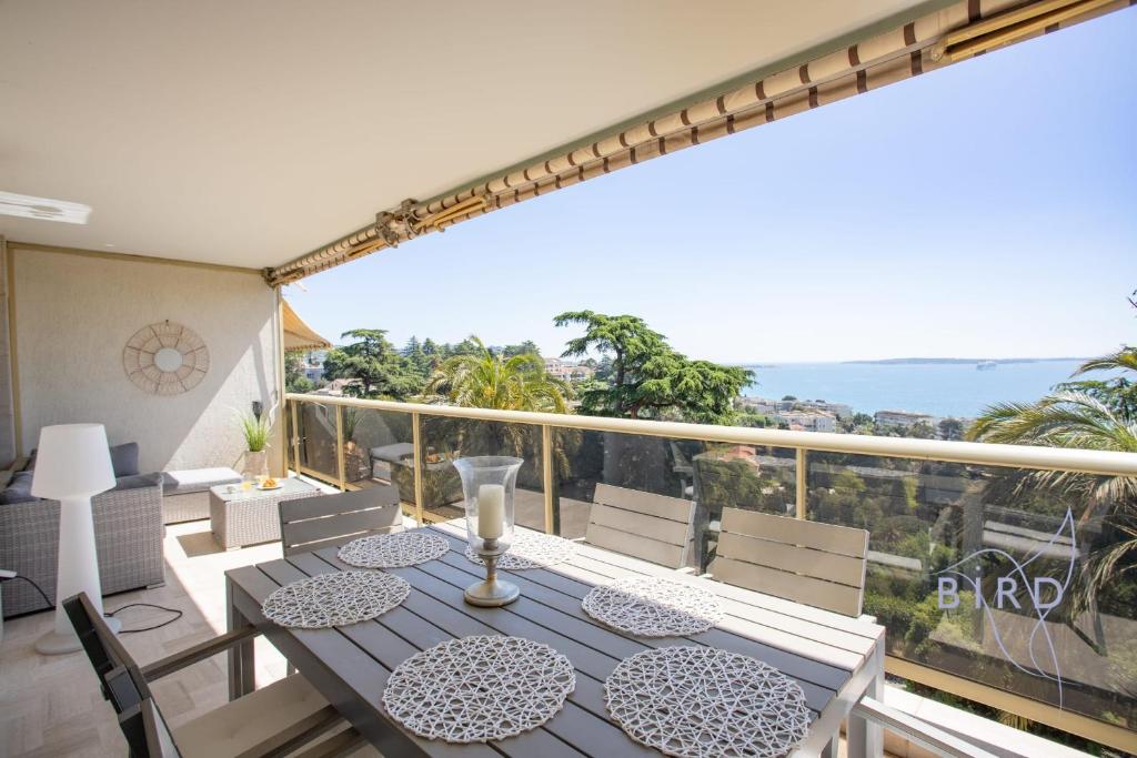un balcon avec une table et des chaises et une vue sur l'océan dans l'établissement Beautiful apartment in Cannes SEA VIEW and POOL, à Cannes