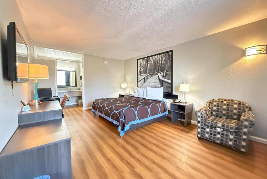 a hotel room with a bed and a chair at Super 8 by Wyndham Hardeeville - Savannah North in Hardeeville