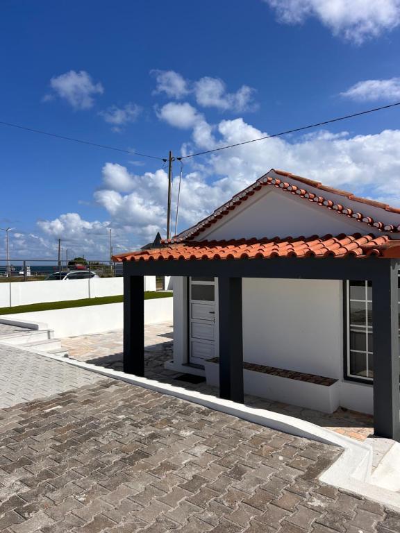 un pequeño edificio blanco con techo rojo en Ninho da Praia, en Baleal