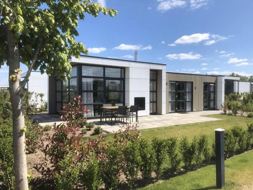 a building with a table and chairs in a garden at Marina Strandbad Chalet SunnyTides Haus Nr 36 in Olburgen