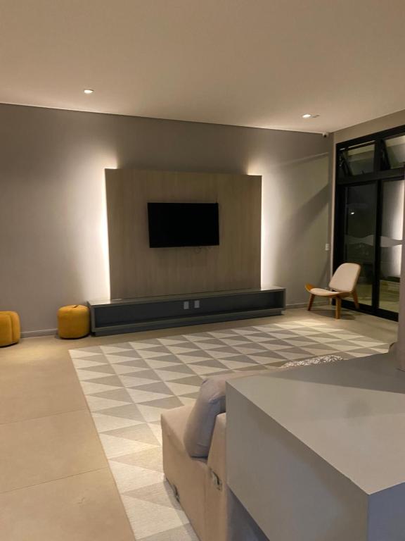 a living room with a couch and a flat screen tv at Quarto Individual Confortável em resort no Brás in Sao Paulo