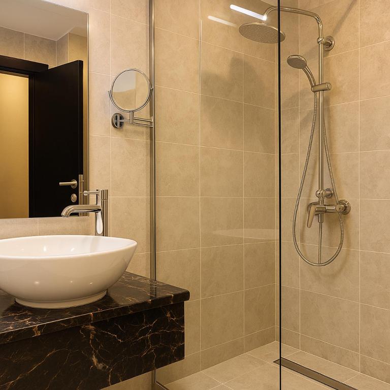 bagno con lavandino e doccia in vetro di Saraya Palace Hotel a Doha