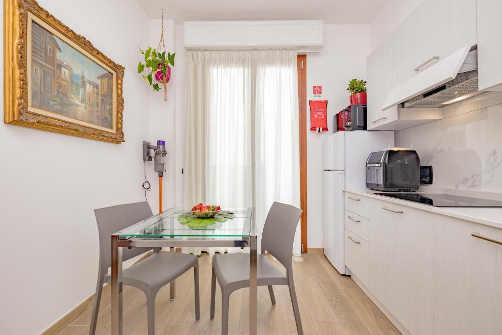 a small kitchen with a glass table and chairs at A8 Aloe Rho Fiera -Milano - MXP AMPIO e LUMINOSO MONOLOCALE in Cesate