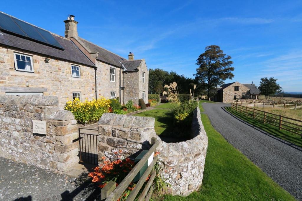 an old stone house with a stone wall at Vesta View & Shepherds Retreat in Hexham