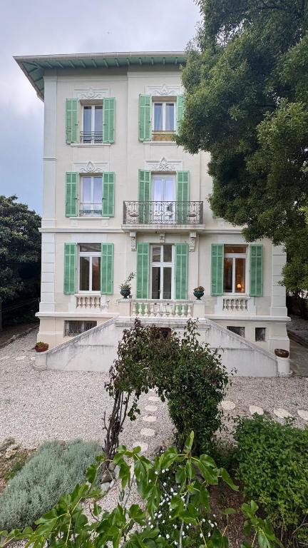 une grande maison blanche avec volets verts dans l'établissement Reine des Mers, à Cannes