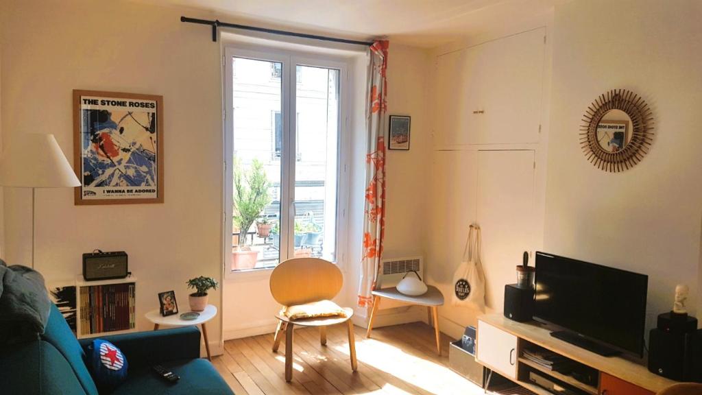 un salon avec un canapé, une télévision et une fenêtre dans l'établissement 2 pièces à Montmatre, à Paris