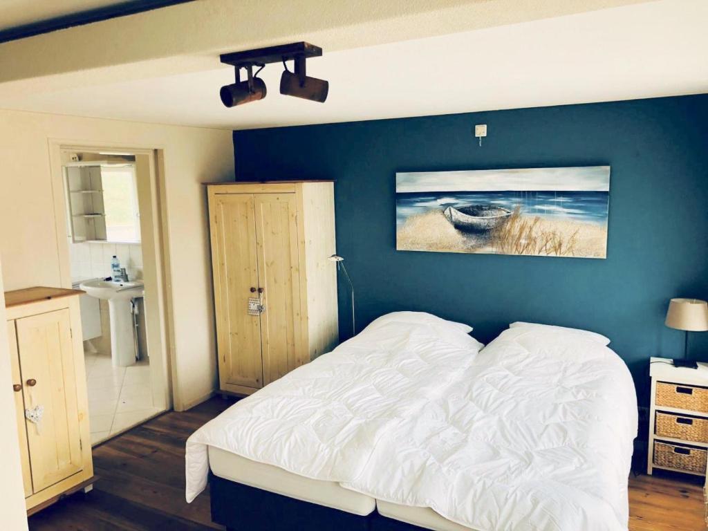 ein Schlafzimmer mit einem weißen Bett und einer blauen Wand in der Unterkunft Fijne vakantiehuizen 50 mtr van het strand in Egmond aan Zee