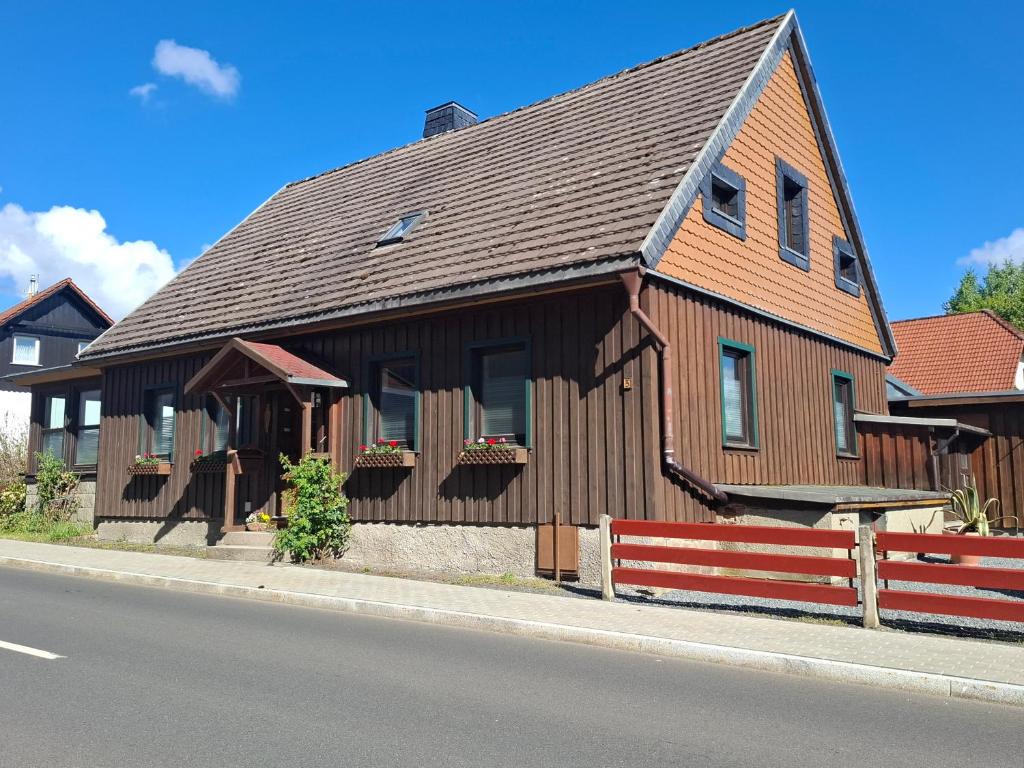 une grande maison en bois avec une clôture sur le côté de la rue dans l'établissement Ferienhaus Willi, à Elend