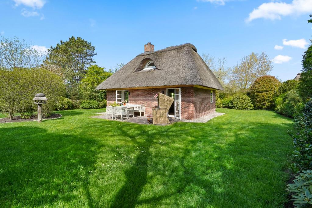 a house with a thatched roof on a lawn at Kampens Herzstück in Kampen