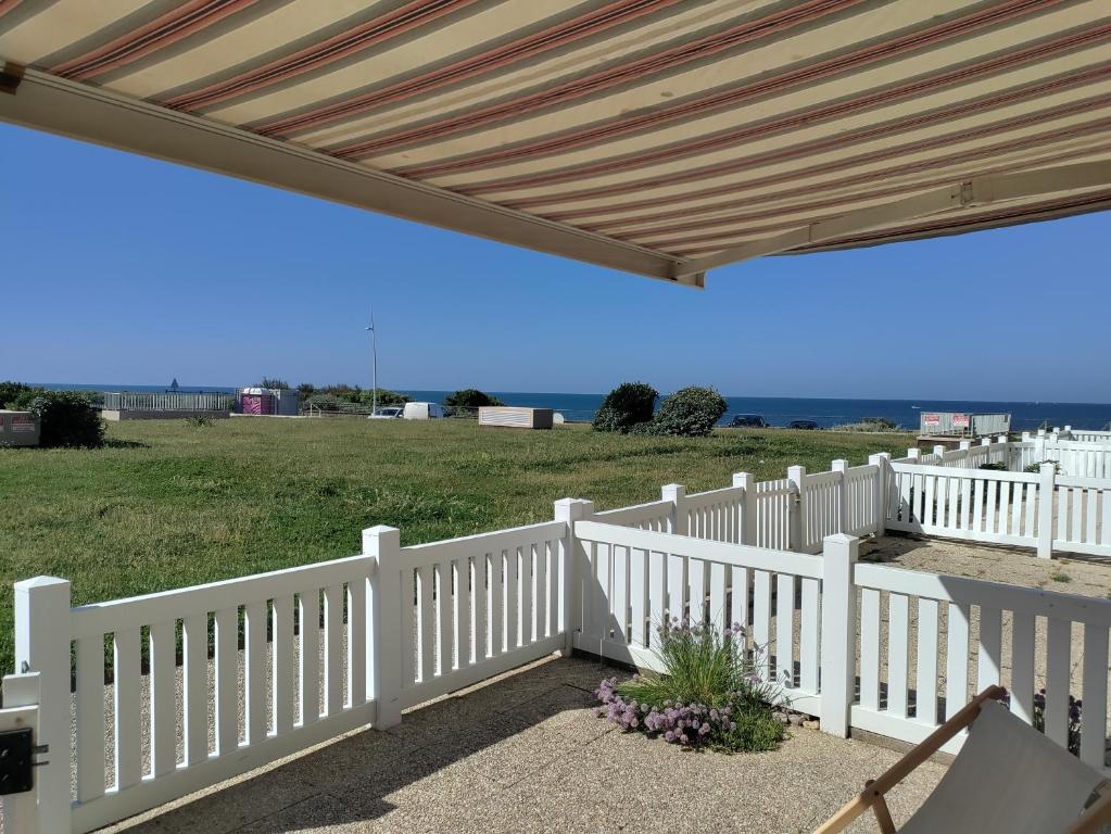 Un porche con una valla blanca y un techo de madera. en Appartement 2 pièces pour 4 personnes avec vue mer, en Saint-Hilaire-de-Riez