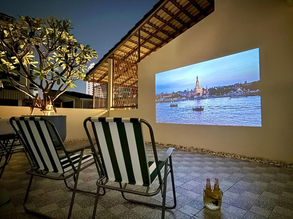una tv appesa a un muro con due sedie di Charming Minimal 3BR Home Near BTS Ari, Bangkok a Sathani Bang Su