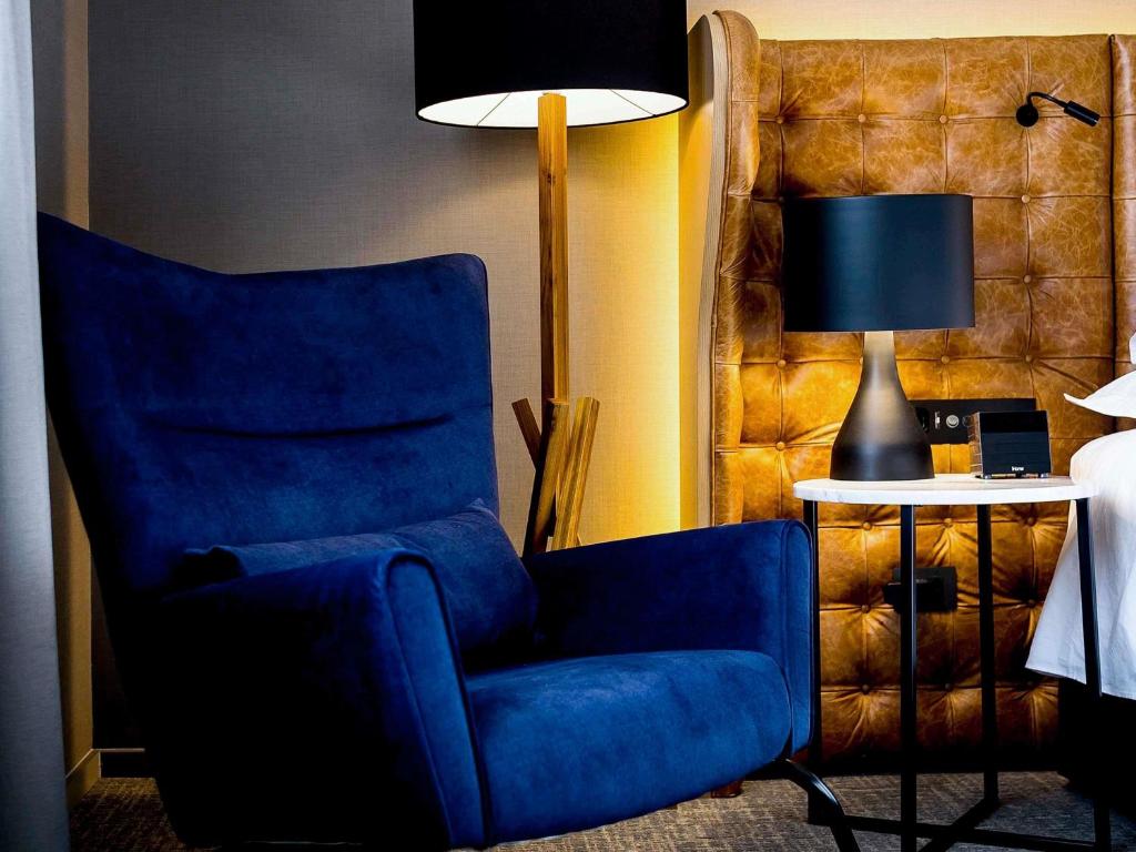 a blue chair and a lamp in a room at Pullman Sao Paulo Guarulhos Airport in Guarulhos