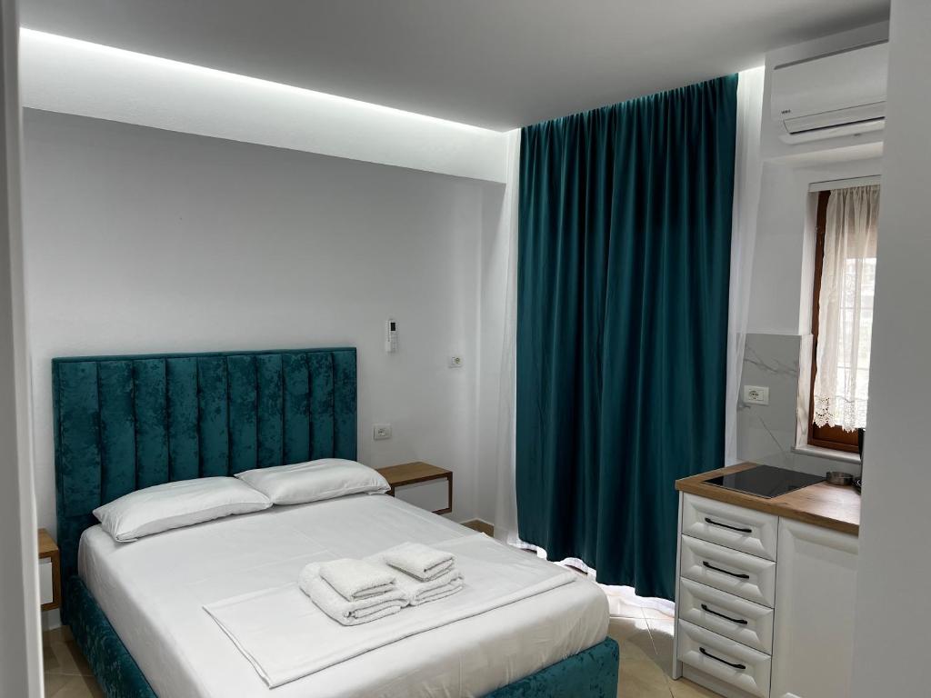 a bedroom with a bed with a green headboard and a sink at Guesthouse Mance in Ksamil