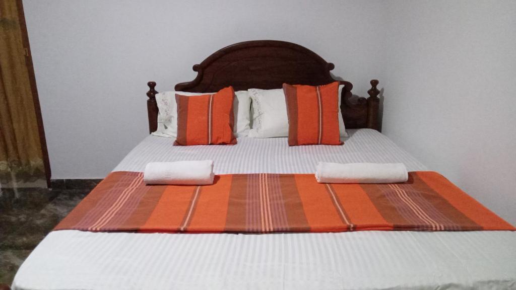 Una cama con almohadas naranjas y blancas. en Star View Kandy, en Kandy