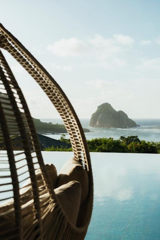 a person in a hammock overlooking a body of water at Pousada Maravilha in Fernando de Noronha