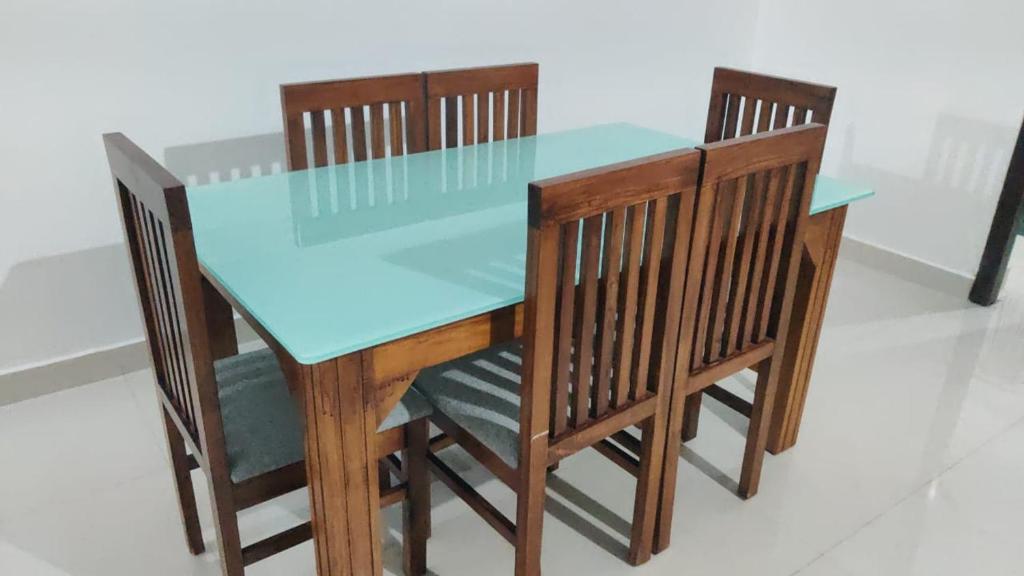 ein Holztisch mit vier Stühlen und einer blauen Tischplatte in der Unterkunft Hill View Residence in Sringeri