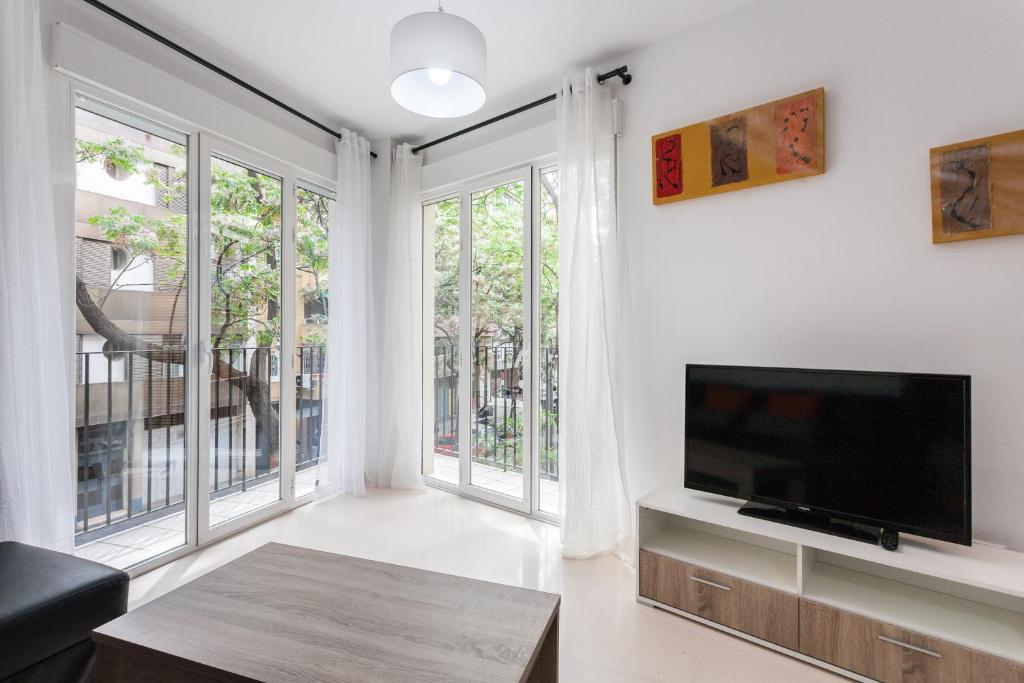 a living room with a flat screen tv and large windows at My Loft 4 You Na Jordana in Valencia