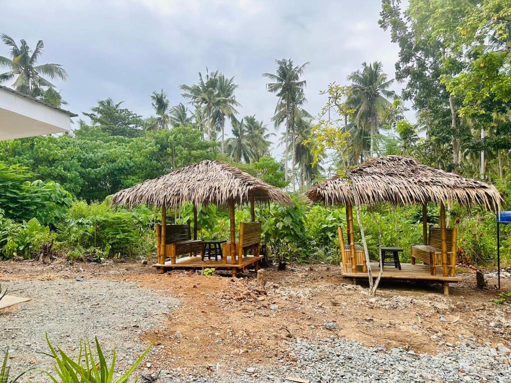 two chairs and umbrellas with trees in the background at La Casita Feliz in Puerto Princesa City