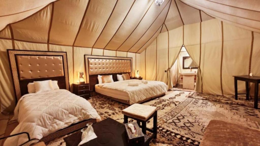 a bedroom with two beds in a tent at Comfort Luxury Camp in Merzouga