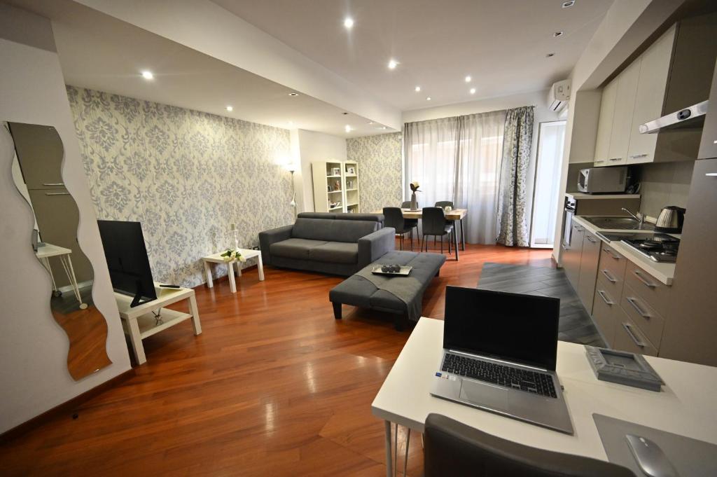 a living room with a couch and a table with a laptop at LA SUITE HOME - Central Apartment Deluxe in Civitavecchia