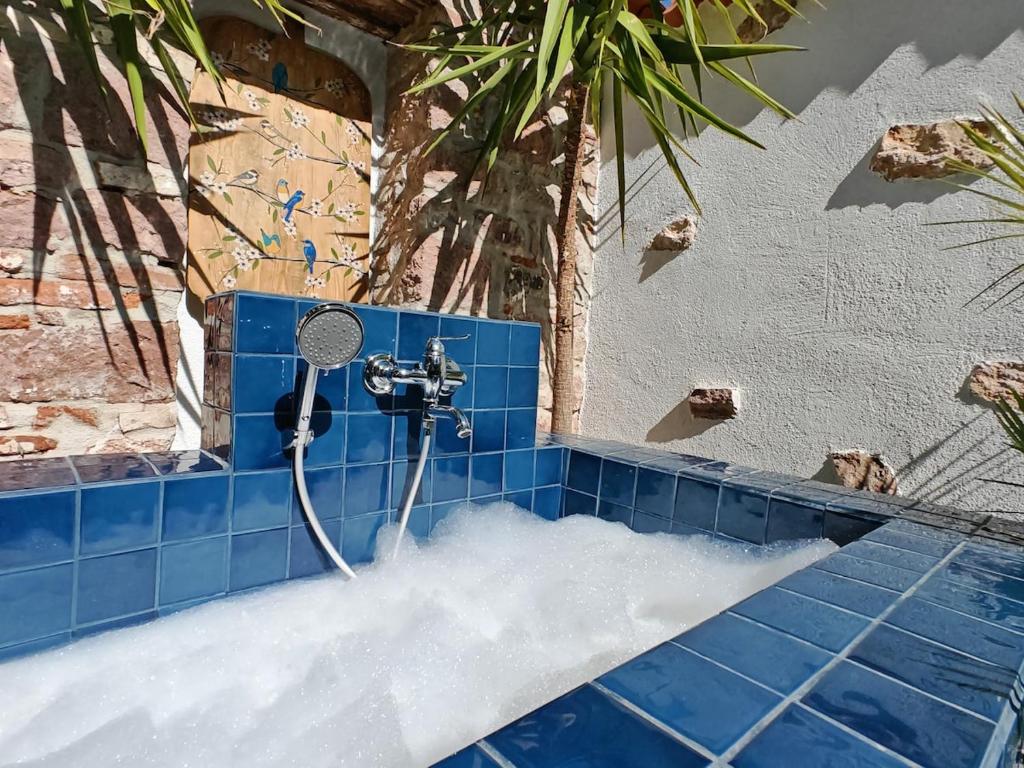 a blue tiled bathroom with a shower with water at Meli Mila Spiti milozrooms Ayvalik in Ayvalık