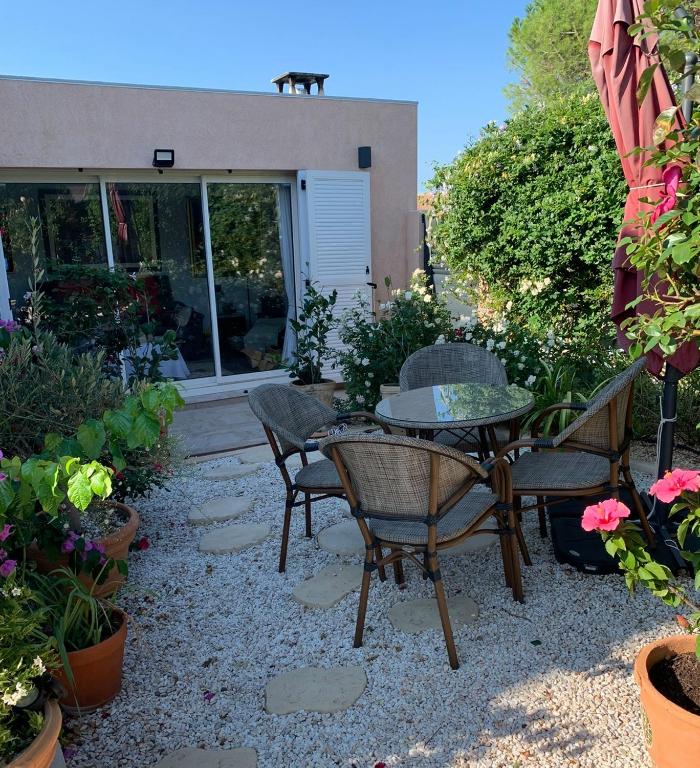 un patio avec une table, des chaises et des plantes dans l'établissement MARSEILLAN Ville, à Marseillan