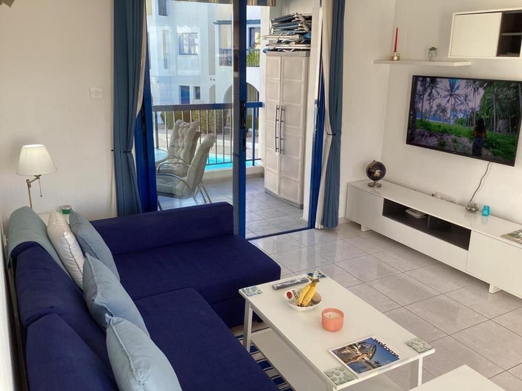 a living room with a blue couch and a tv at paphos pool view gem - cozy 1 bed Apartment in Paphos