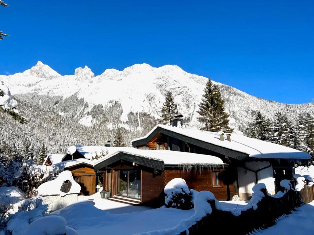 a house covered in snow with a mountain in the background at Chalet Claudia in Scharnitz