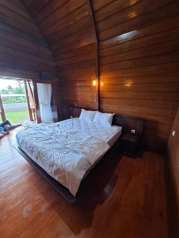 a bedroom with a bed in a wooden wall at Rinjani Koceng Bungalow in Tetebatu