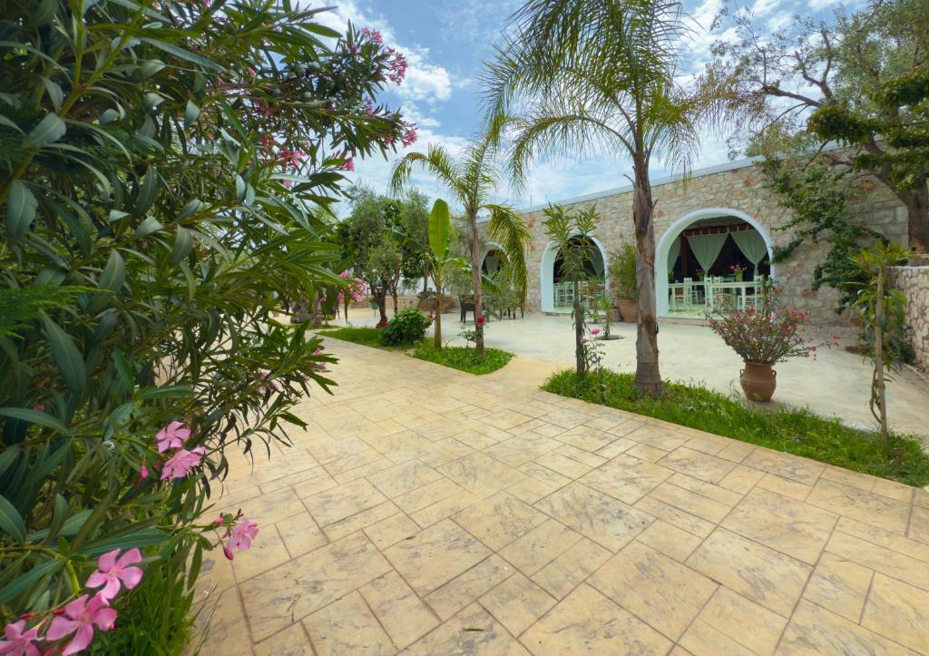 a courtyard with a building and trees and flowers at Rida Village Ksamil Island in Ksamil